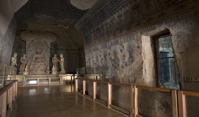 Interior of a decorated Buddhist cave with a central shrine and mural walls