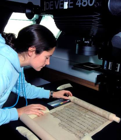 Researcher studying an unfurled historic manuscript