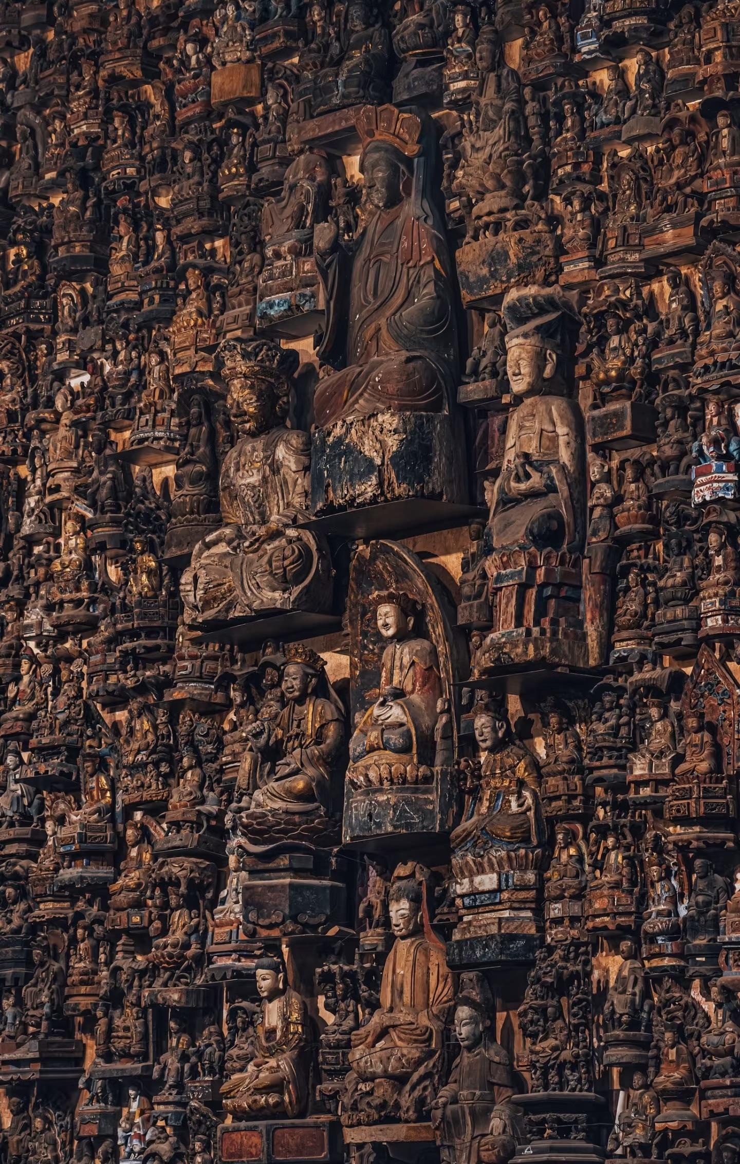 Dense wall of carved wooden Buddhist figures used as a material and devotional art reference